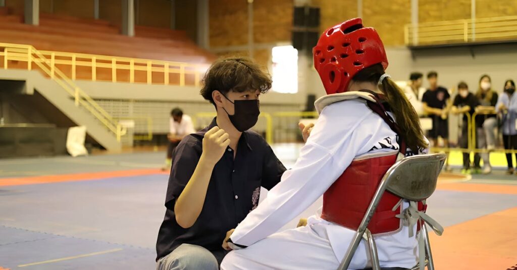 Coach gives motivational talk to a taekwondo athlete during an indoor competition.