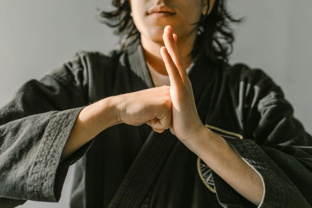 sportification pratiques martiales Close-up of a martial artist in black gi showing a respectful hand gesture during training.